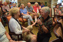 a group of people sitting in chairs and talking to a dog